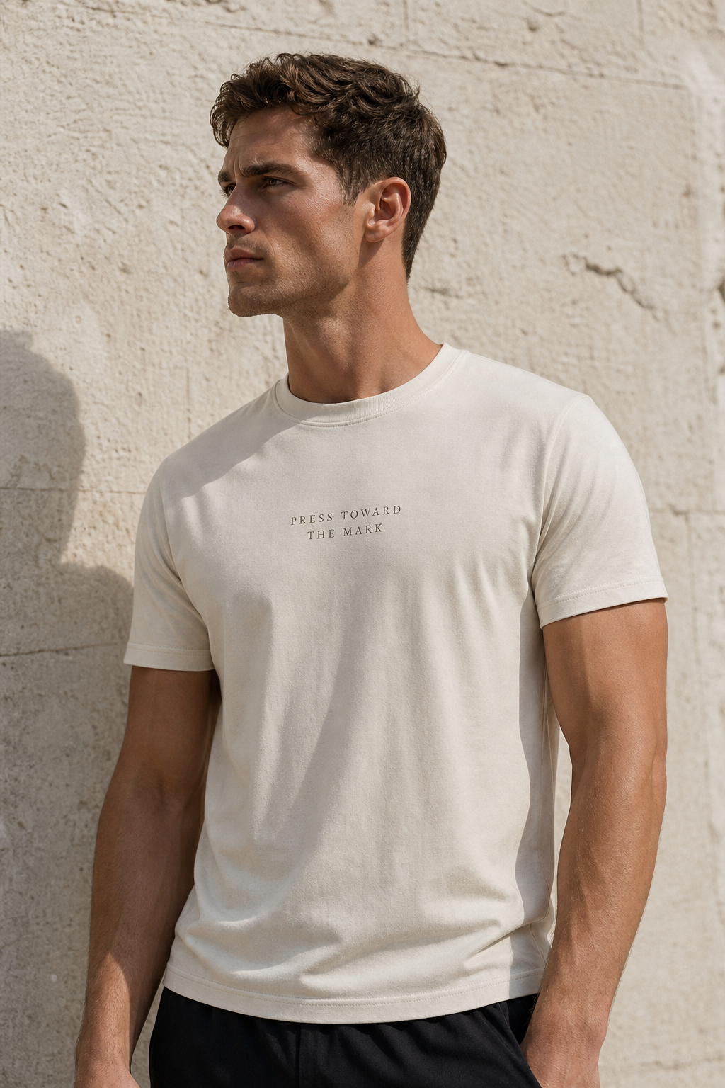 PRESS TOWARD THE MARK, small and letterspaced, tonal on a men’s bone cotton tee.